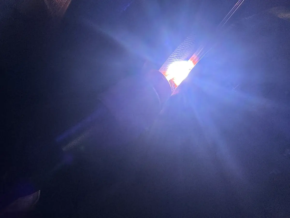 Bright blue and white light rays burst outward in a dark setting, creating a glowing starburst effect against a mostly black background.